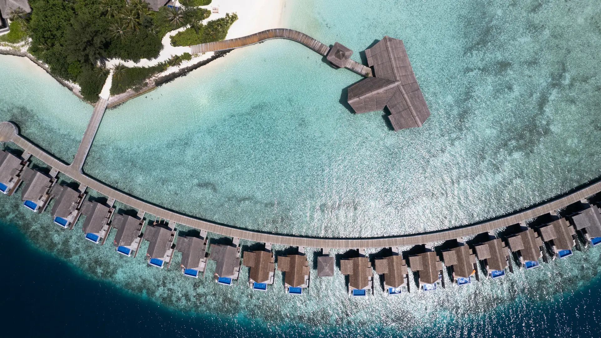 Overwater villas curving across a turquoise tropical lagoon