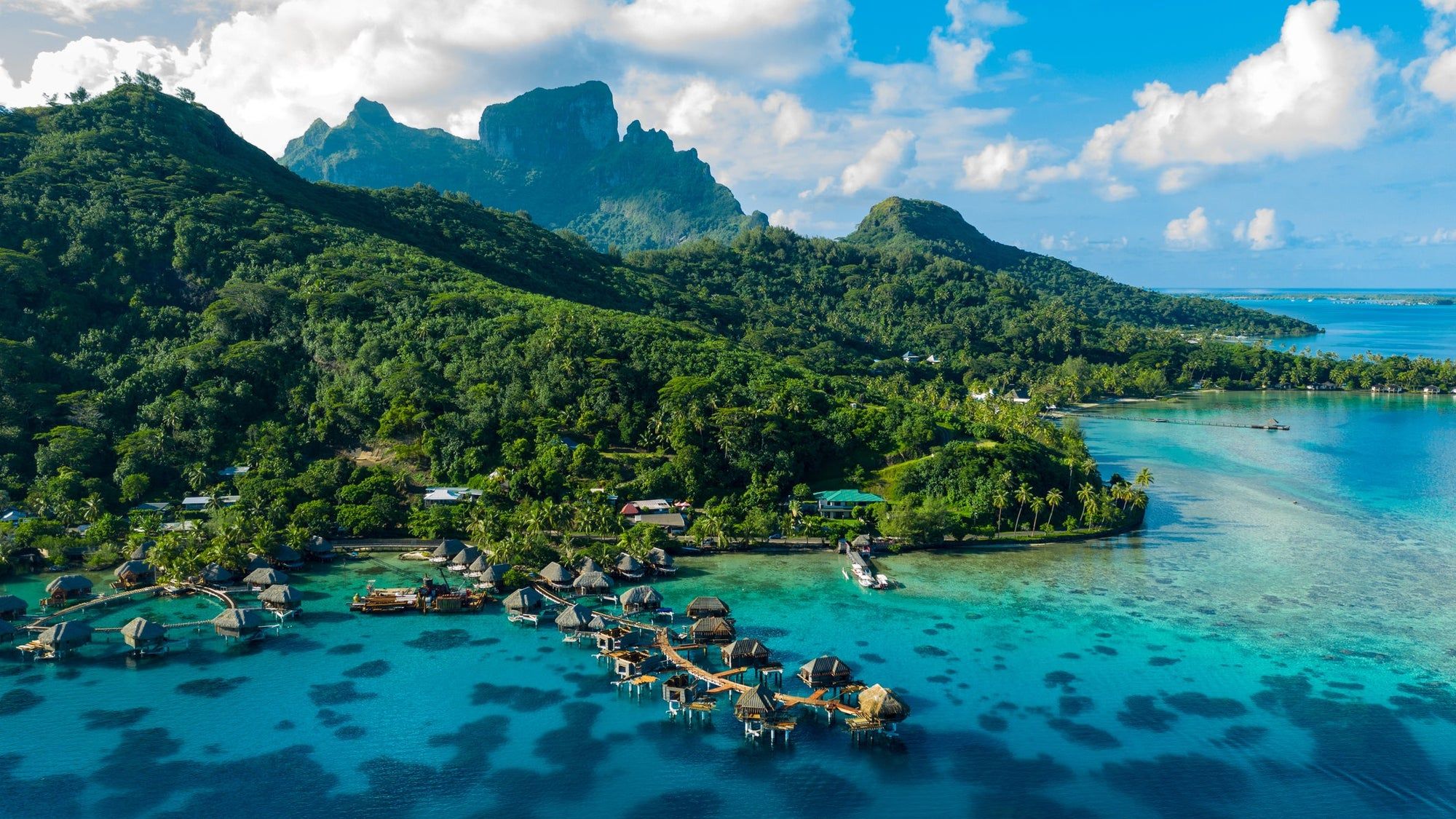 Aerial view of Bora Bora's turquoise lagoon, overwater bungalows, and Mount Otemanu