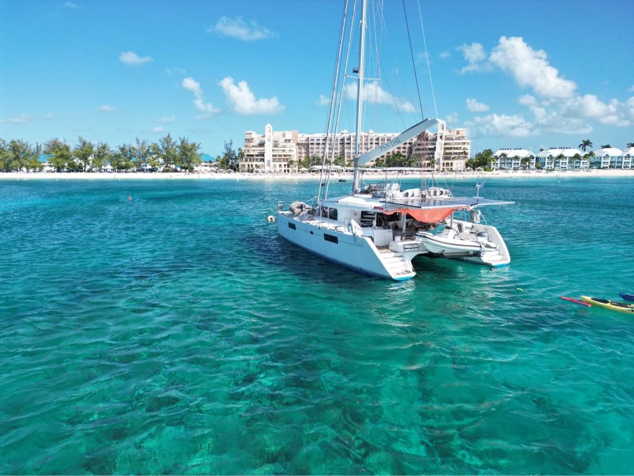 A white catamaran anchored in crystal-clear turquoise water off Grand Cayman