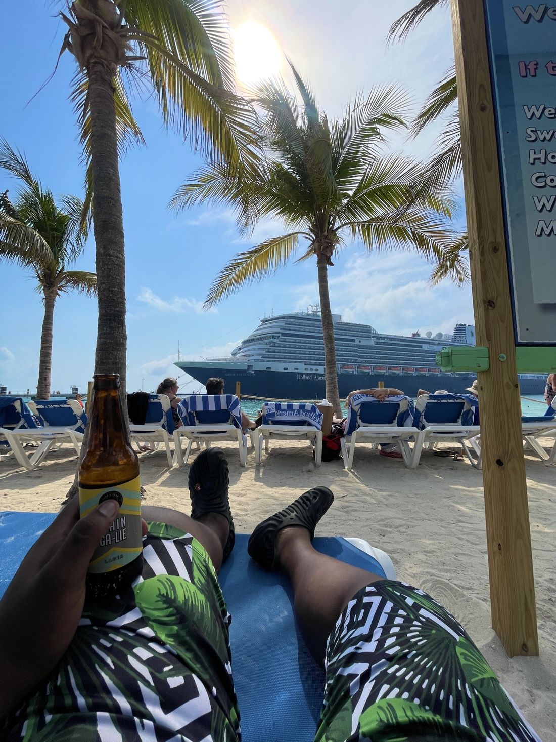 Lounging on the beach with a Holland America cruise ship anchored behind the palms