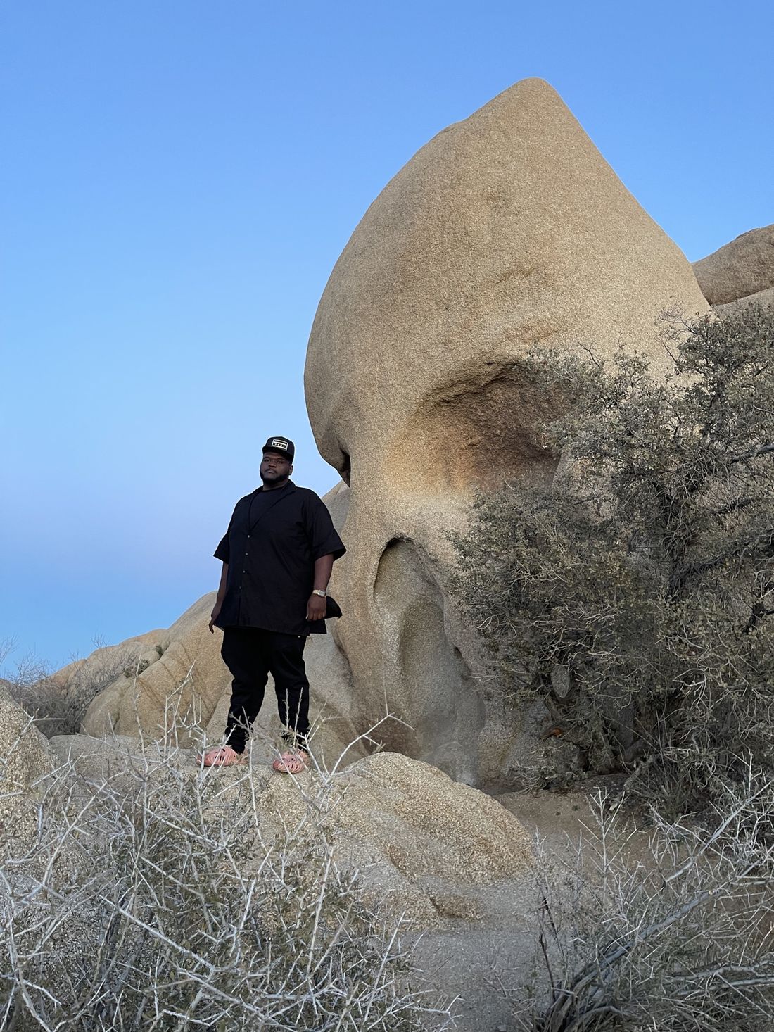 Tam standing on boulders beside Skull Rock at dusk